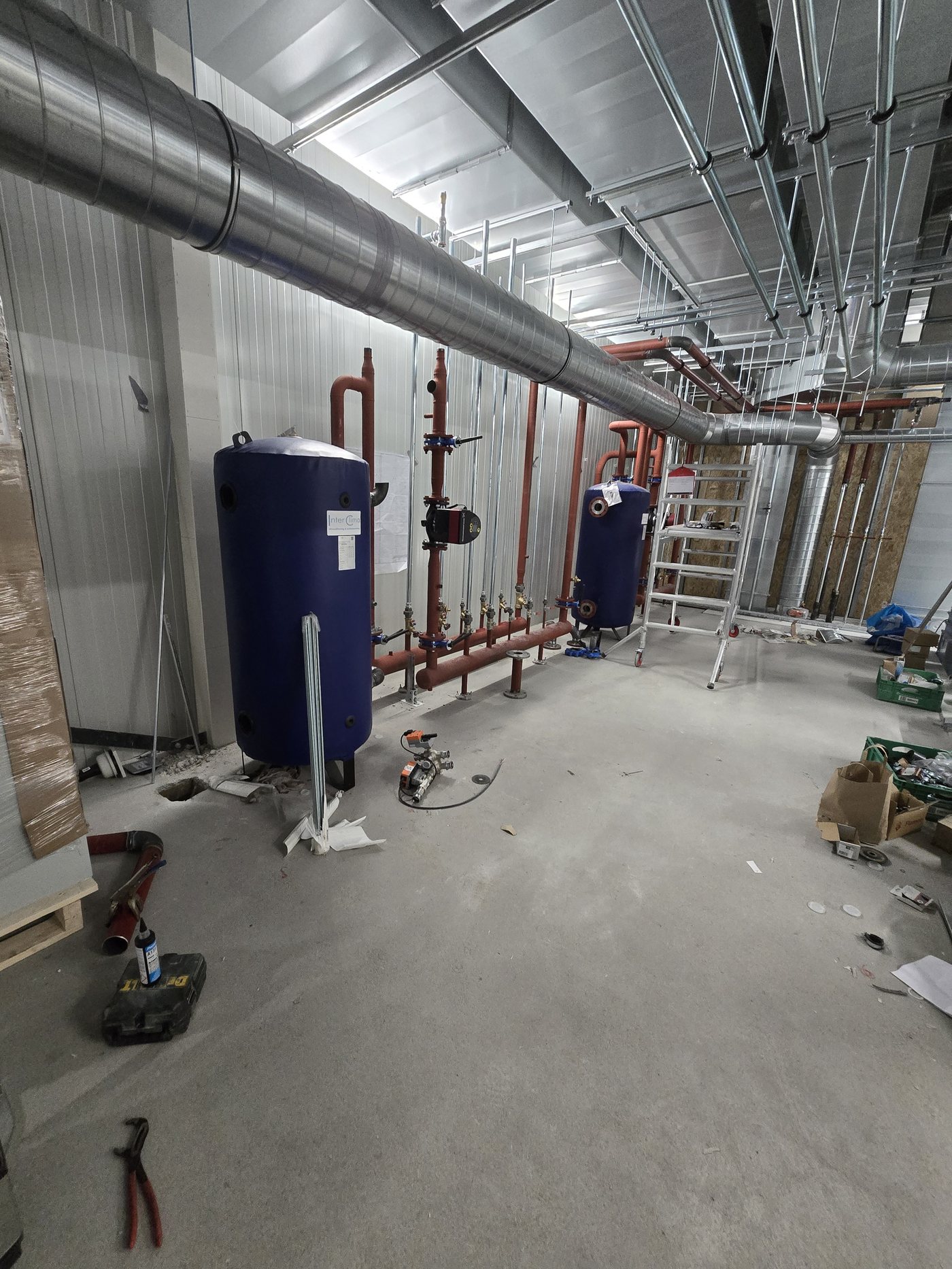 Technische ruimte met leidingwerk en boilervaten tijdens onderhoud aan een installatie