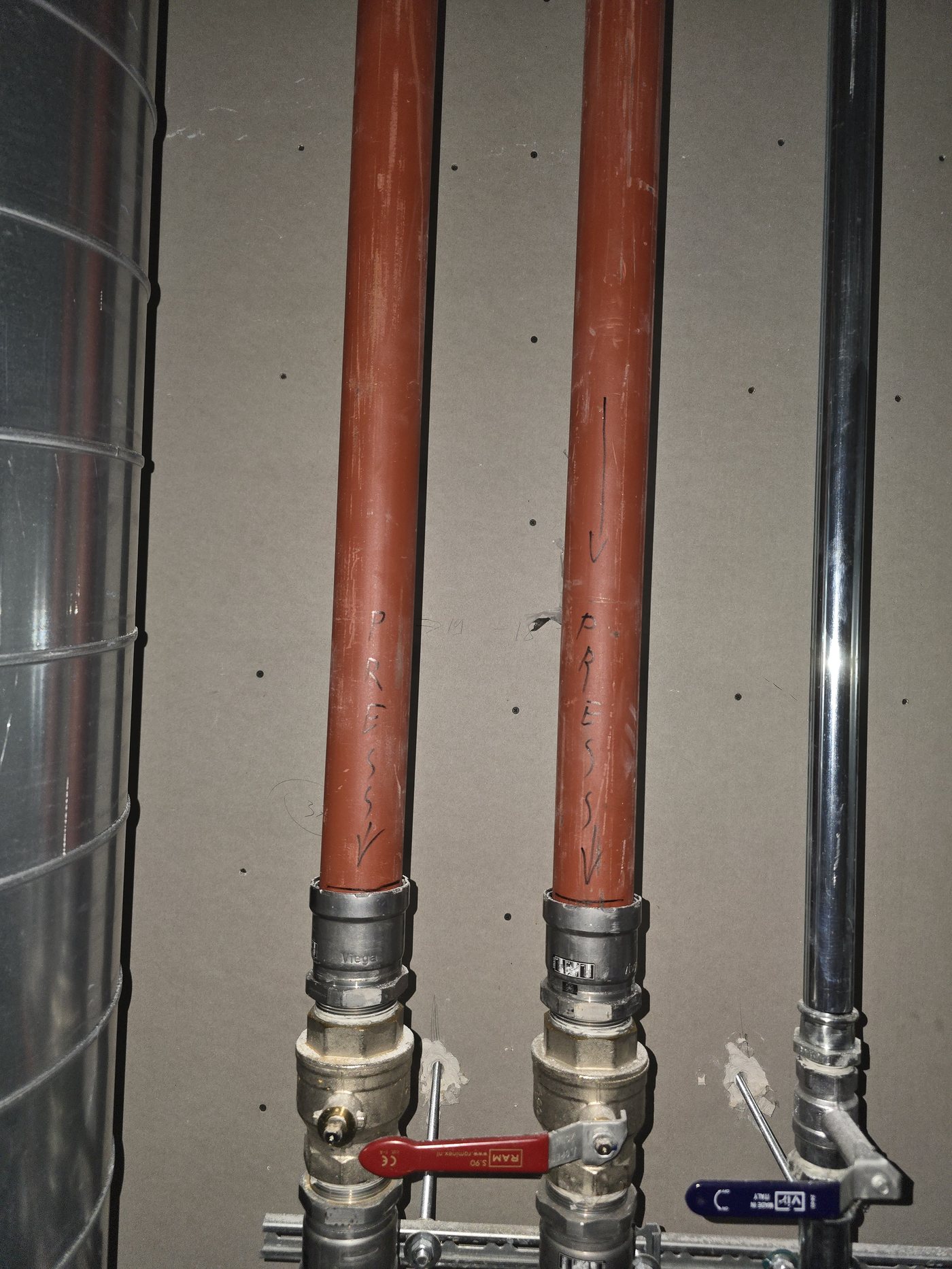 Verticale leidingen in rood en zwart langs de gevel