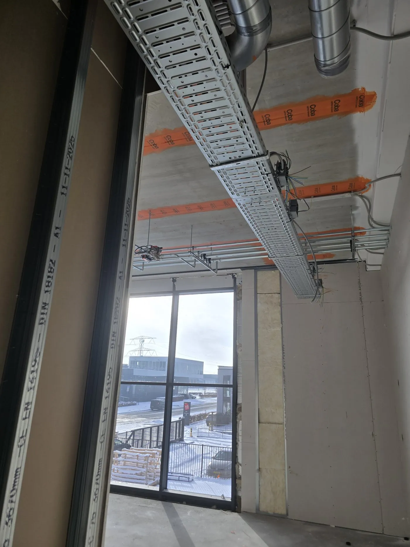 Cable tray and pipework on the ceiling, with a view outside