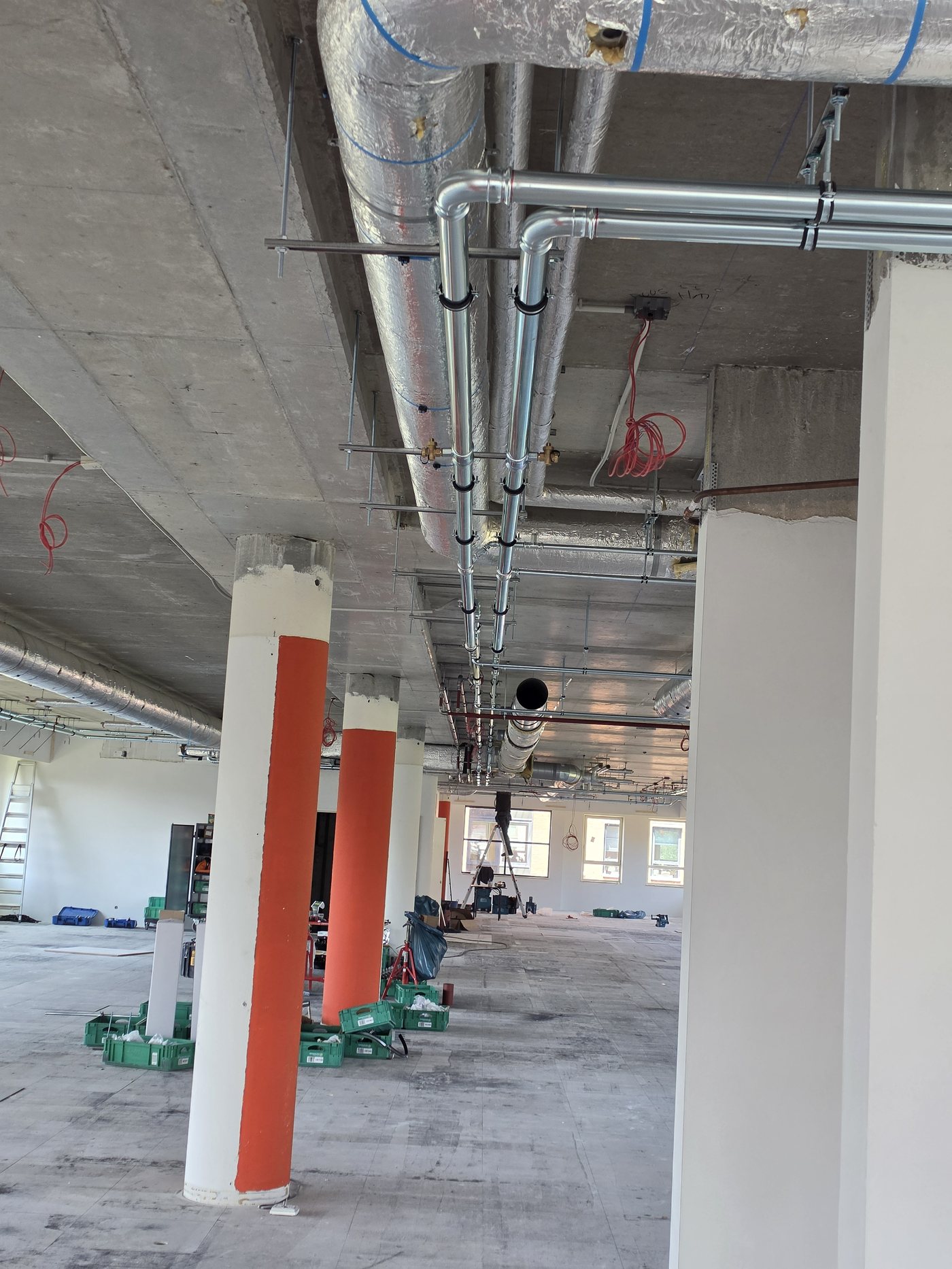 Leidingwerk langs het plafond tussen de betonkolommen op de kantoorverdieping