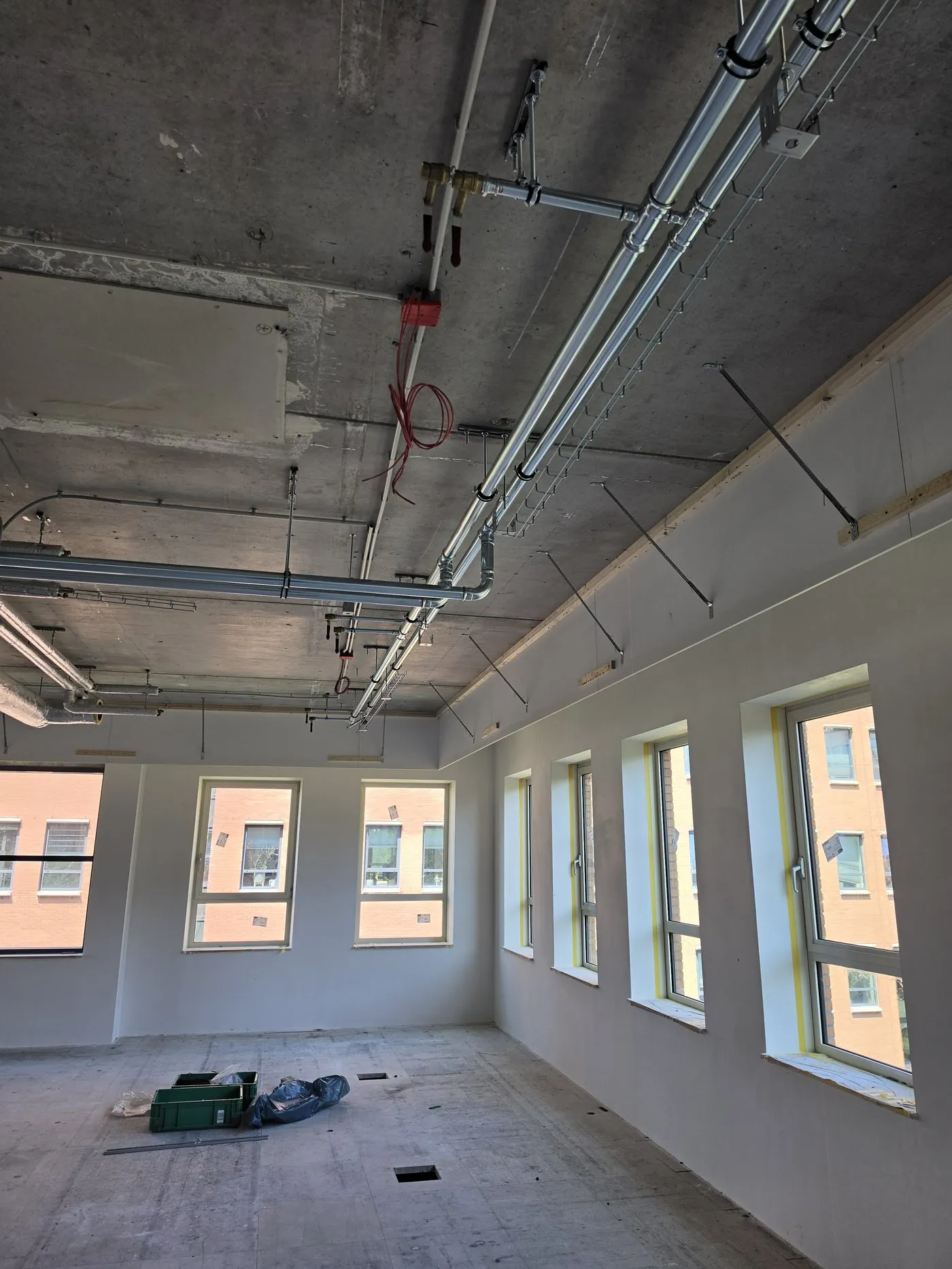 Office space under construction with pipework on the ceiling
