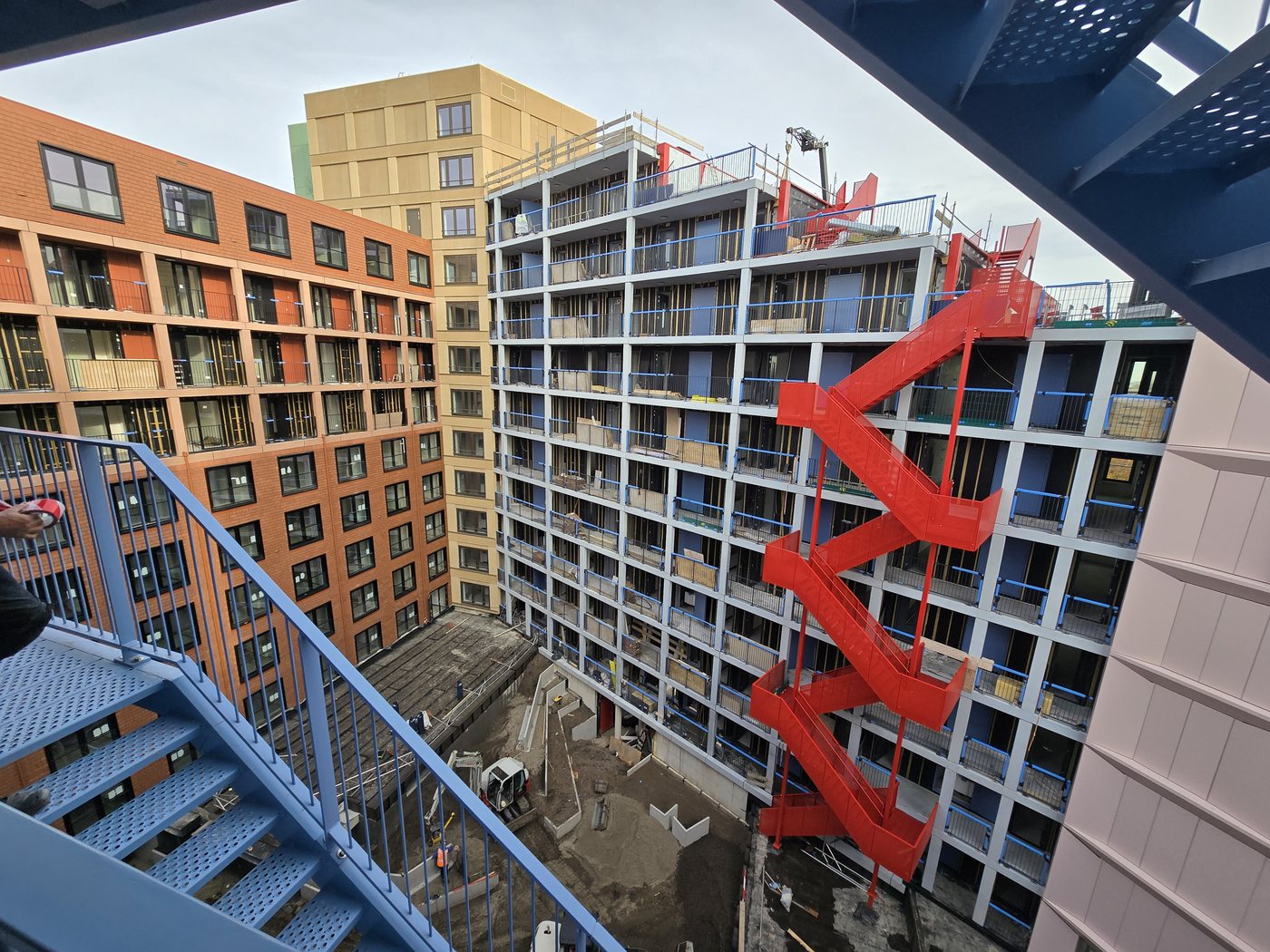 Binnenplaats van het woongebouw Camden Town in Hoofddorp, met een rode brandtrap langs de gevel
