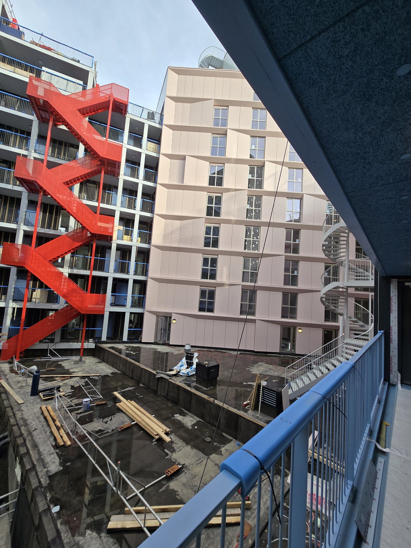 Binnenplaats van het woongebouw Camden Town in Hoofddorp, met een rode brandtrap langs de gevel