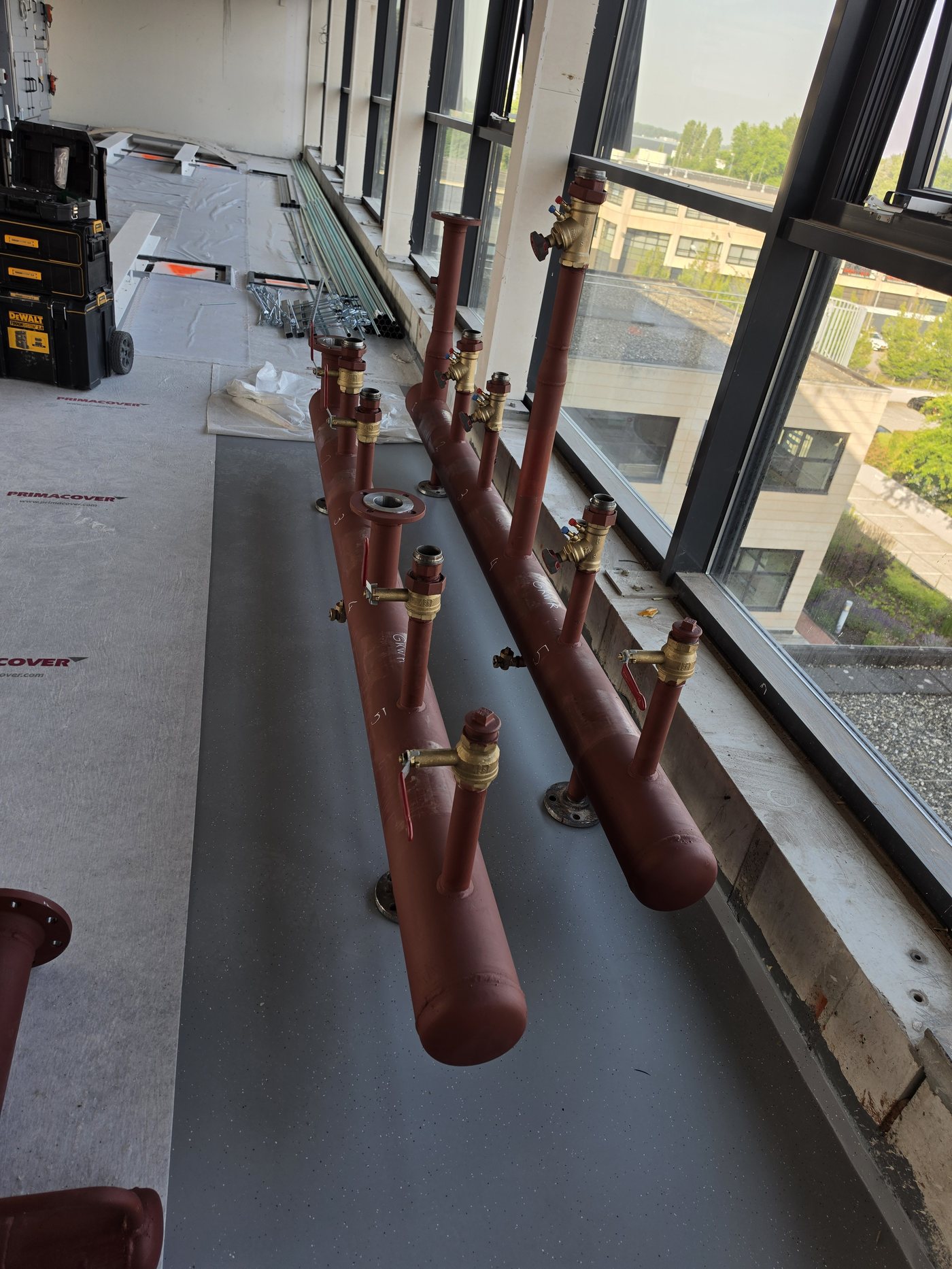 Rij koperen manifolds met afsluiters langs de gevel