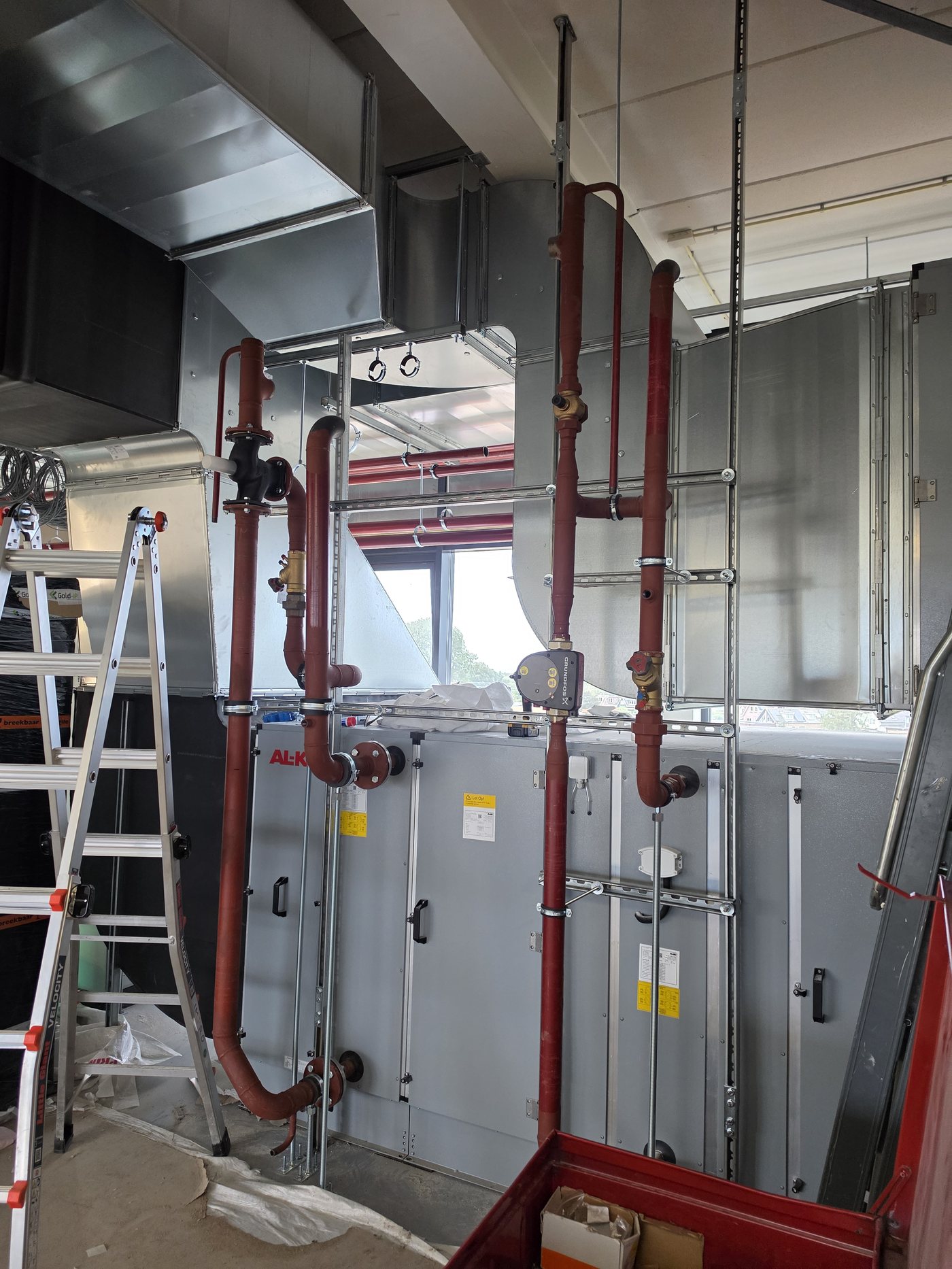 Monteur op een ladder tijdens de installatie van leidingwerk
