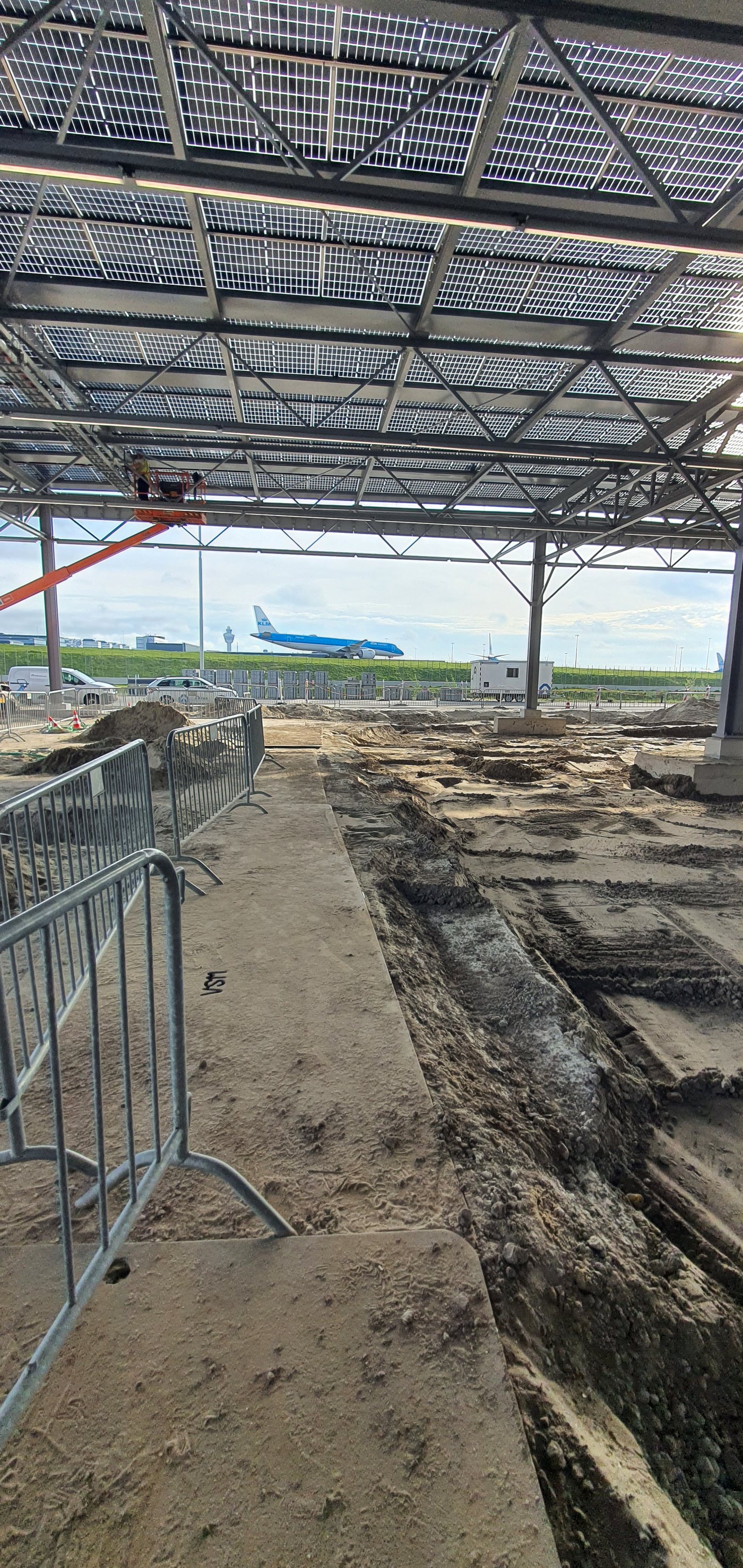 Graafwerkzaamheden voor het drainagesysteem, met een vliegtuig op de achtergrond
